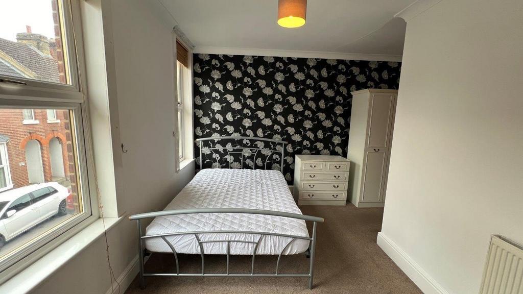 Bright double bedroom with patterned feature wa...