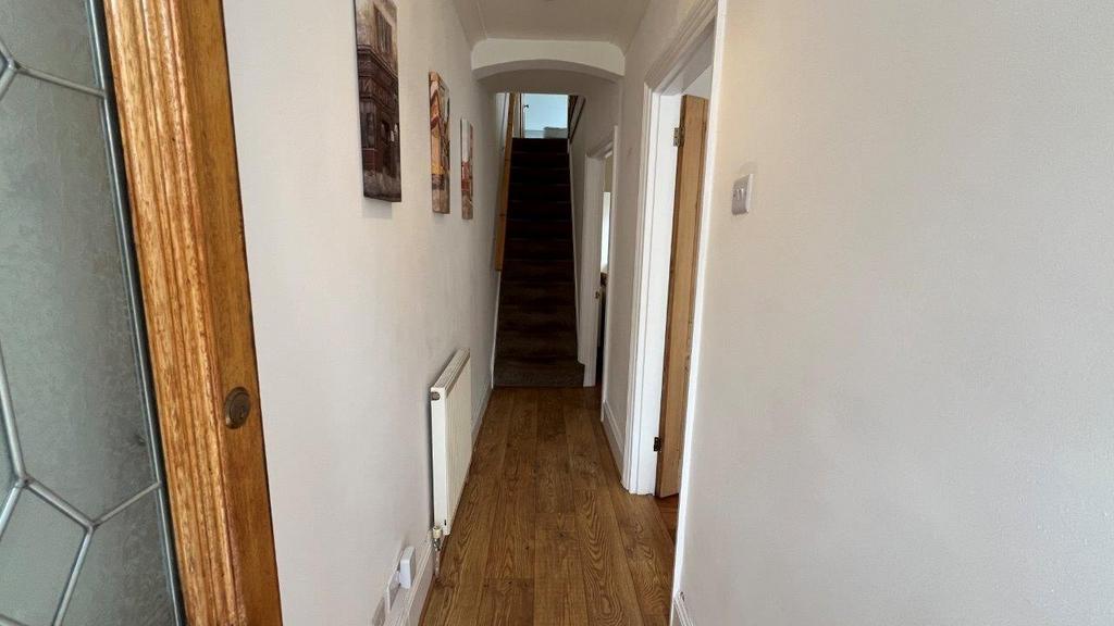 Bright, tidy hallway with wood flooring and sta...