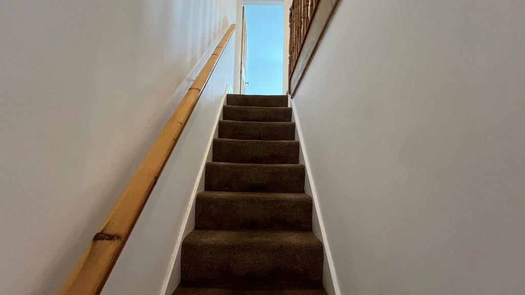 Carpeted stairway with handrail and natural lig...