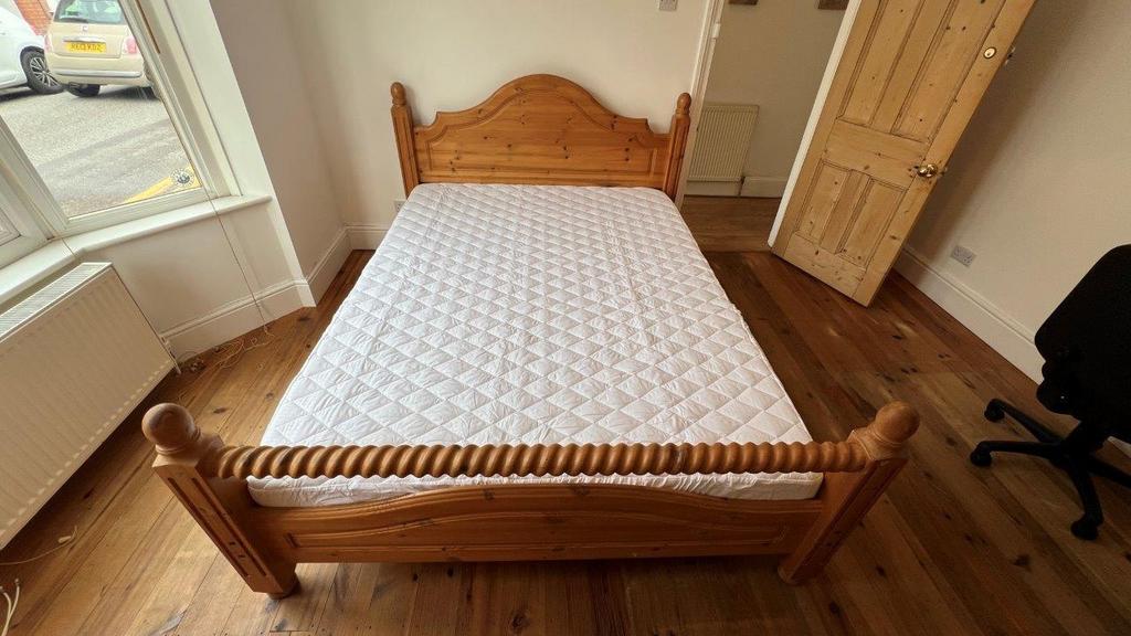 Bright double bedroom with wooden bed and floor...