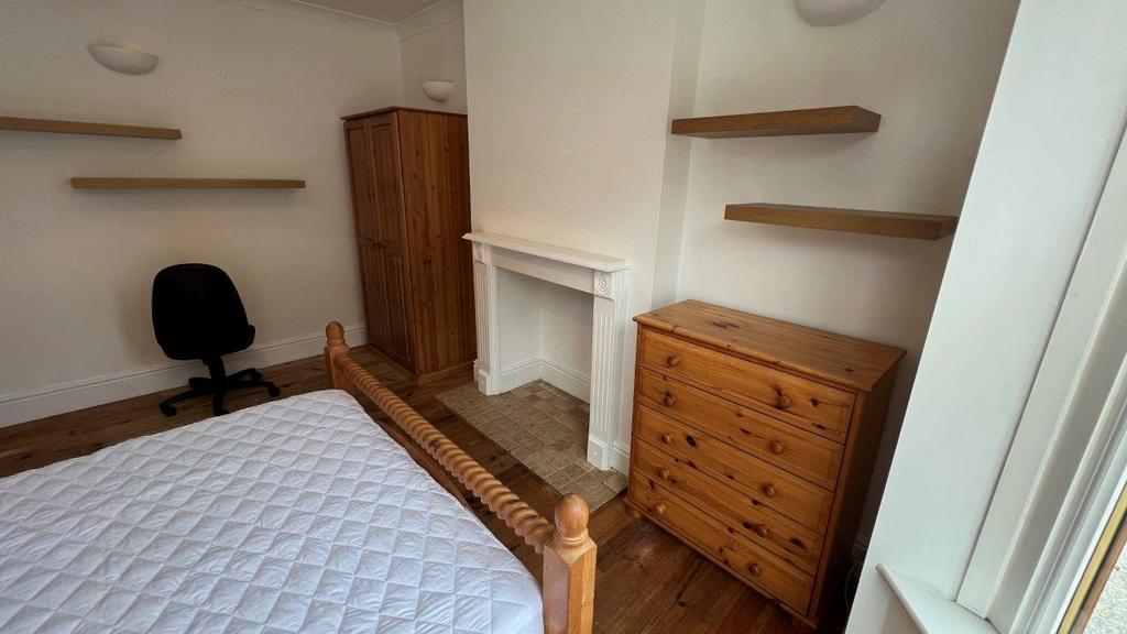 Bright bedroom with wooden furniture and shelvi...