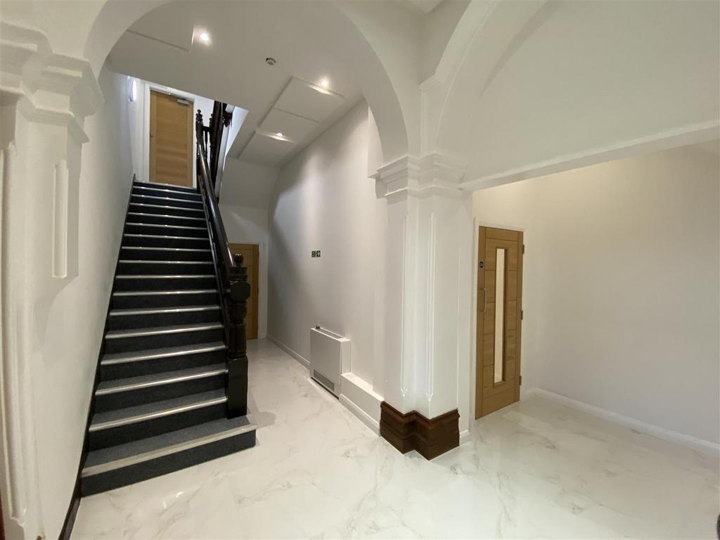 Elegant hallway with grand staircase and arches...
