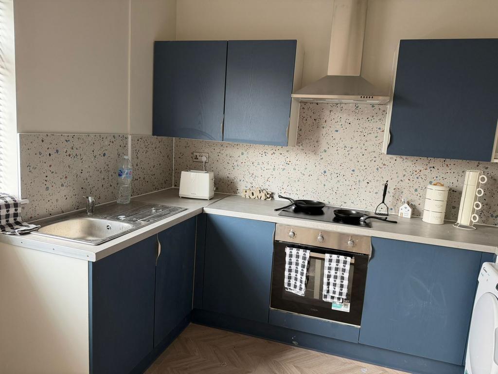 Modern kitchen with blue units and chic splashb...