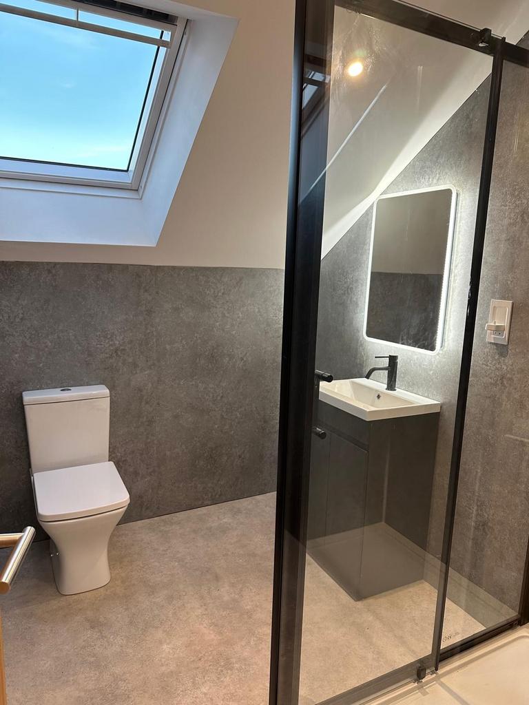 Modern attic bathroom with a skylight, sleek wa...