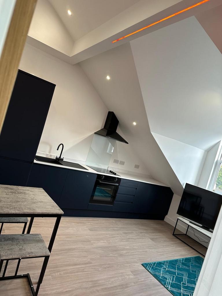 Modern open-plan kitchenette with sleek dark ca...