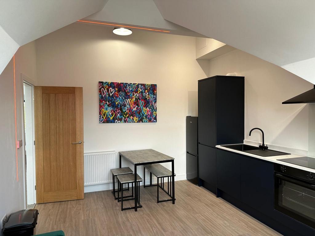 Modern open-plan kitchenette with sleek black c...