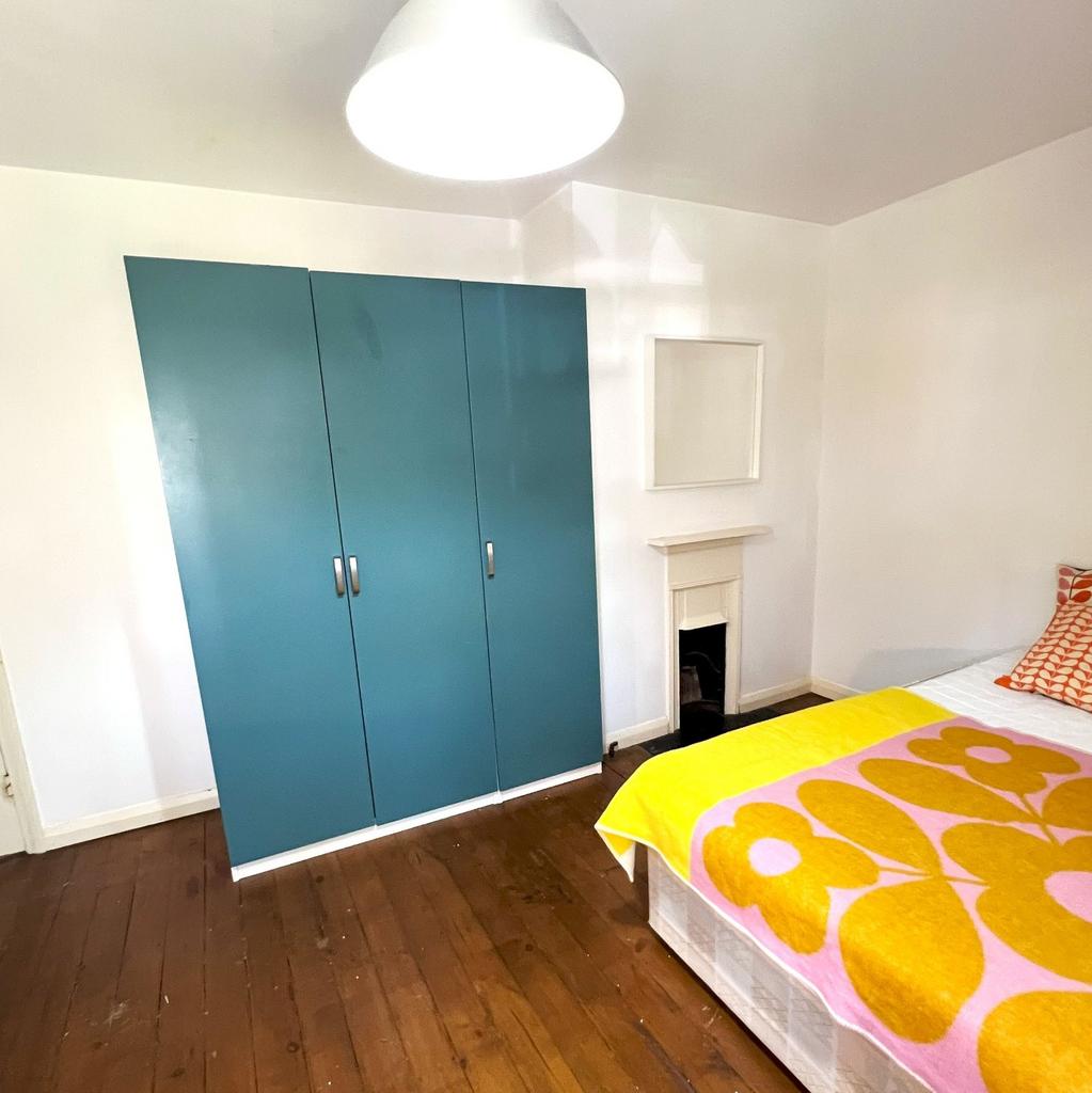 Bright double bedroom with colourful bedding, a...