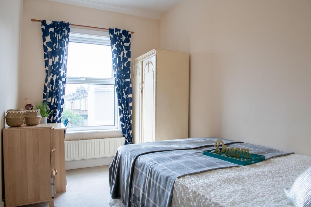 Bright, neatly styled bedroom with a large wind...