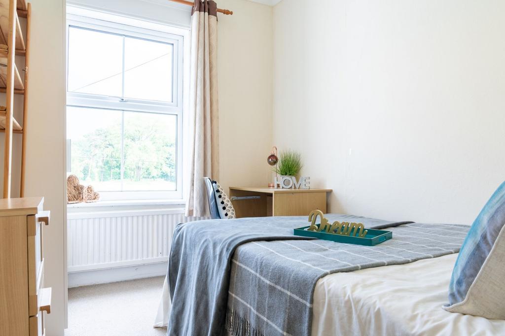 Bright, neatly styled bedroom with a large wind...