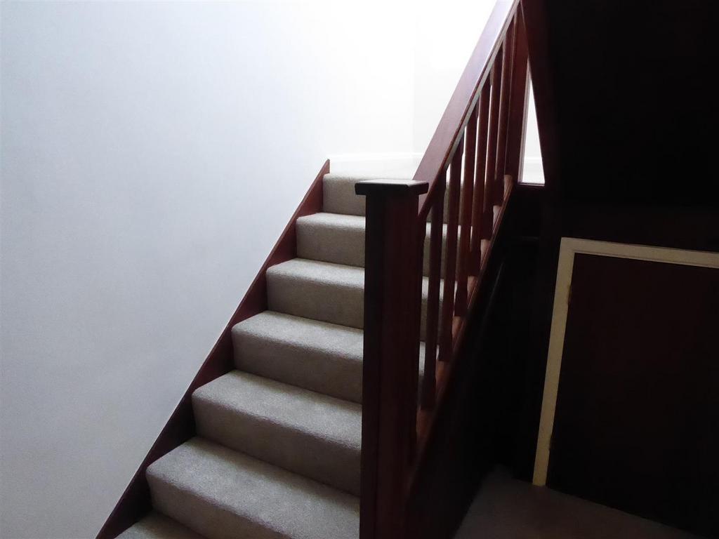 Bright carpeted staircase with wood banister...