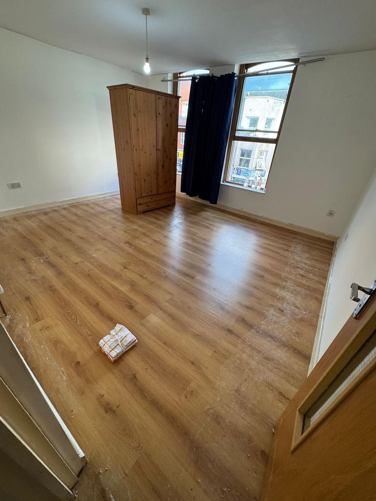 Spacious bright bedroom with sleek wood floorin...