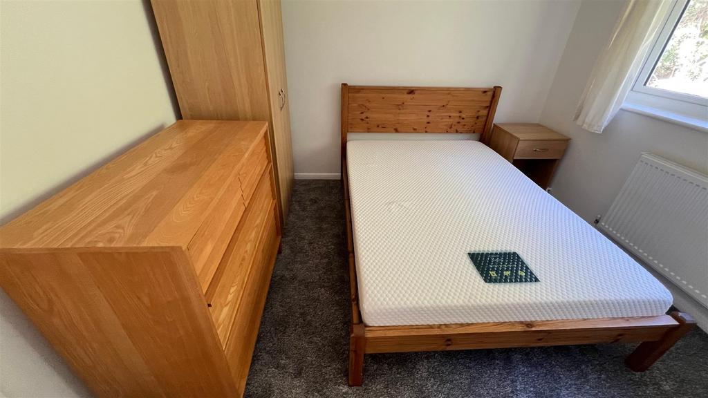 Bright bedroom with wooden bed and storage...