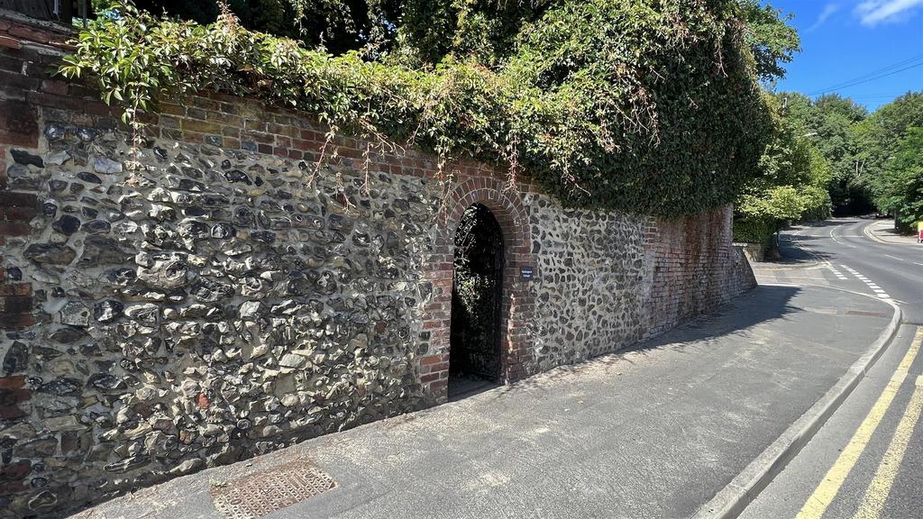 Characterful stone wall with arched pedestrian ...