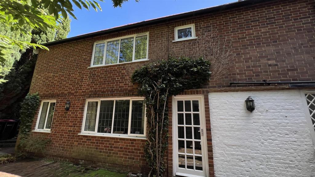 Brick-front house with driveway and mature tree...