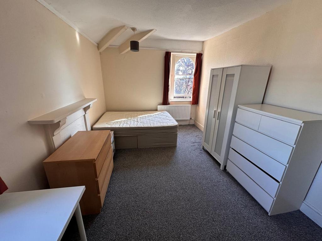 Bright, simply furnished bedroom with a single ...