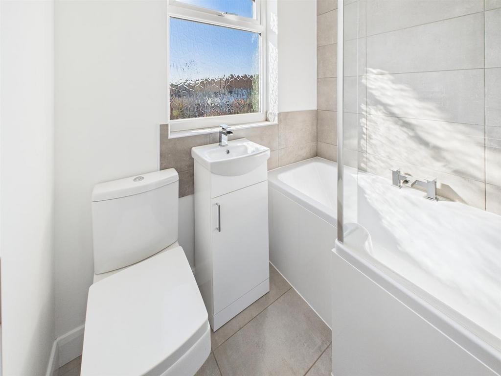 Modern bathroom with bright window and full bat...
