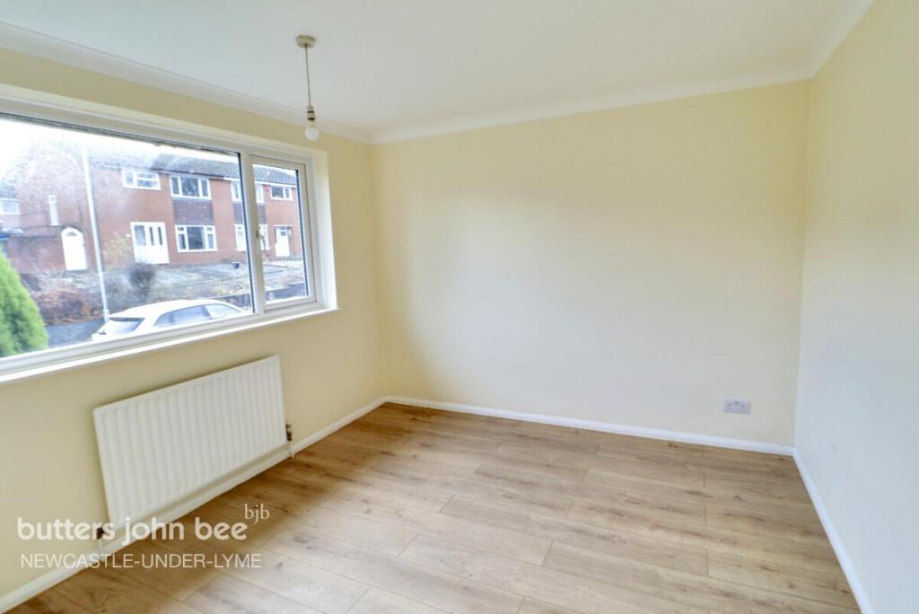 Bright bedroom with large window and wood floor...