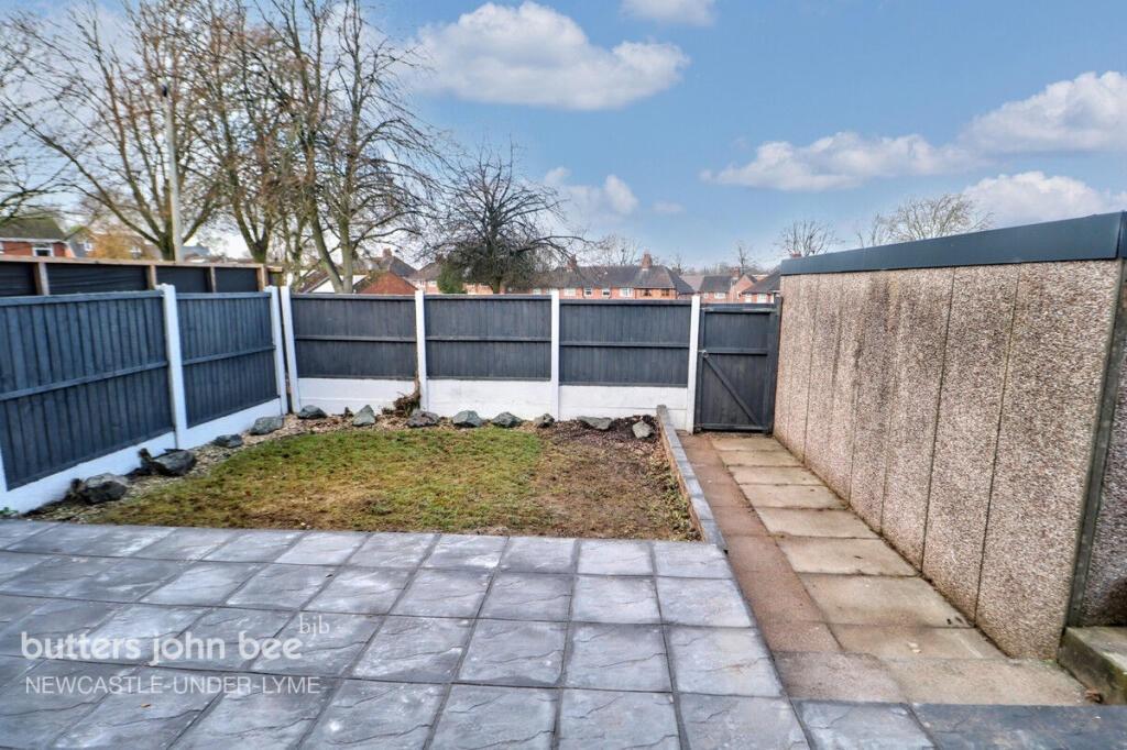 Low-maintenance paved garden with lawn and pati...