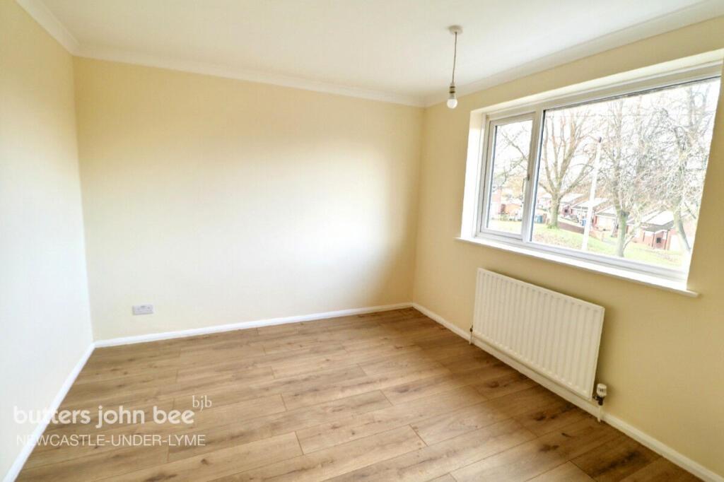 Bright bedroom with large window and wooden flo...