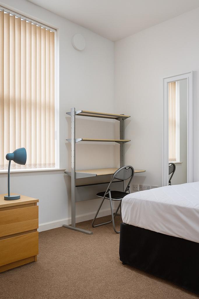 Well-lit furnished bedroom with a neat bed, com...