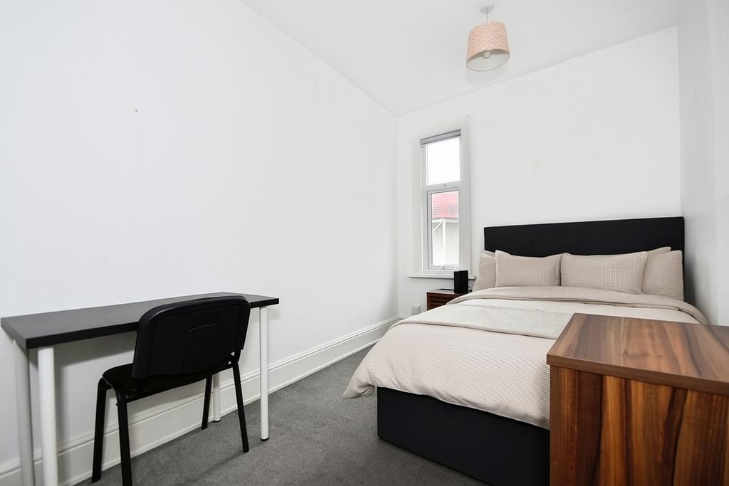 Bright, neatly furnished bedroom with a double ...