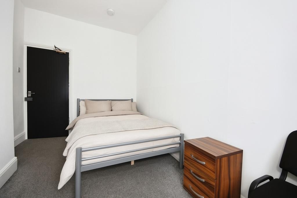 Bright, simply furnished bedroom with a metal d...