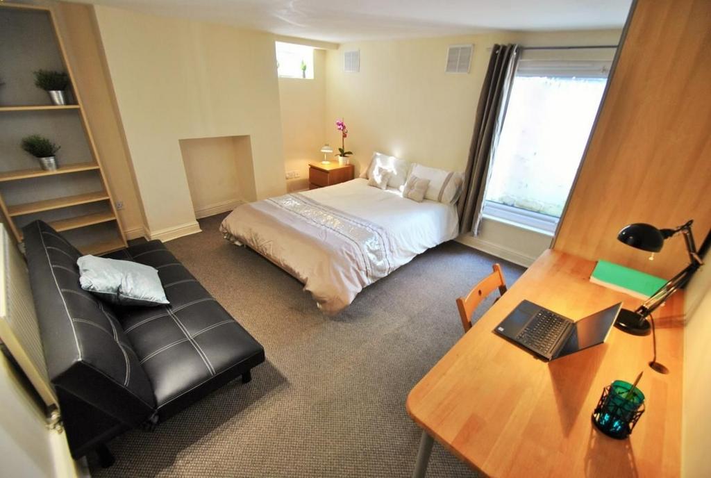 Bright bedroom with sofa, desk and storage spac...