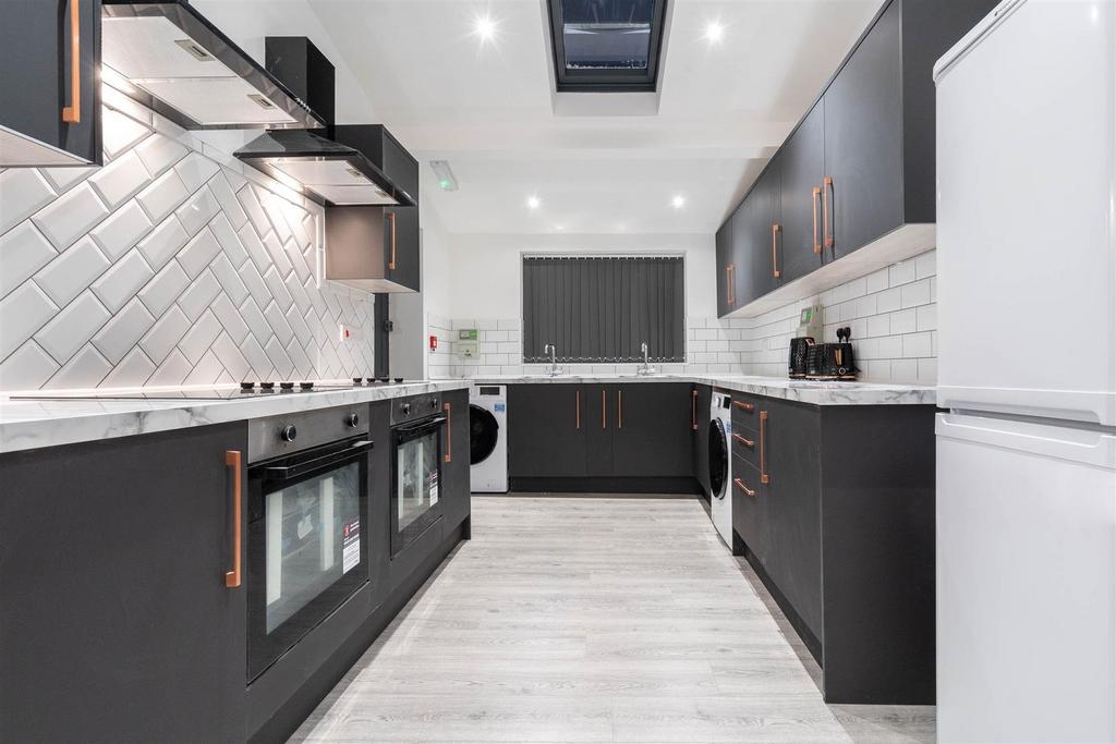 Modern kitchen with sleek dark units and skylig...