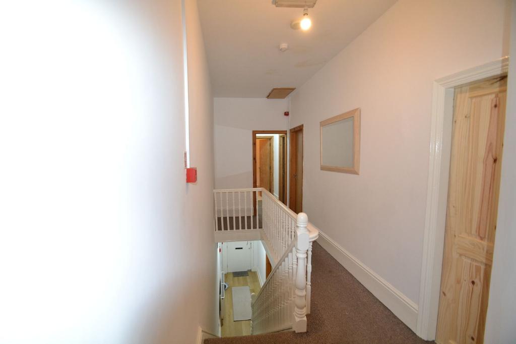 Bright upstairs hallway with neutral walls, car...