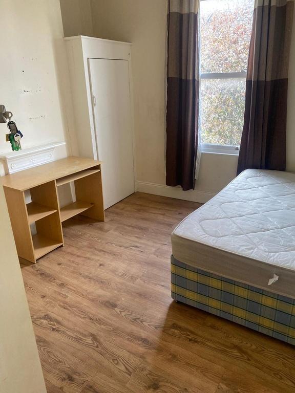Bright bedroom with desk and wood flooring...