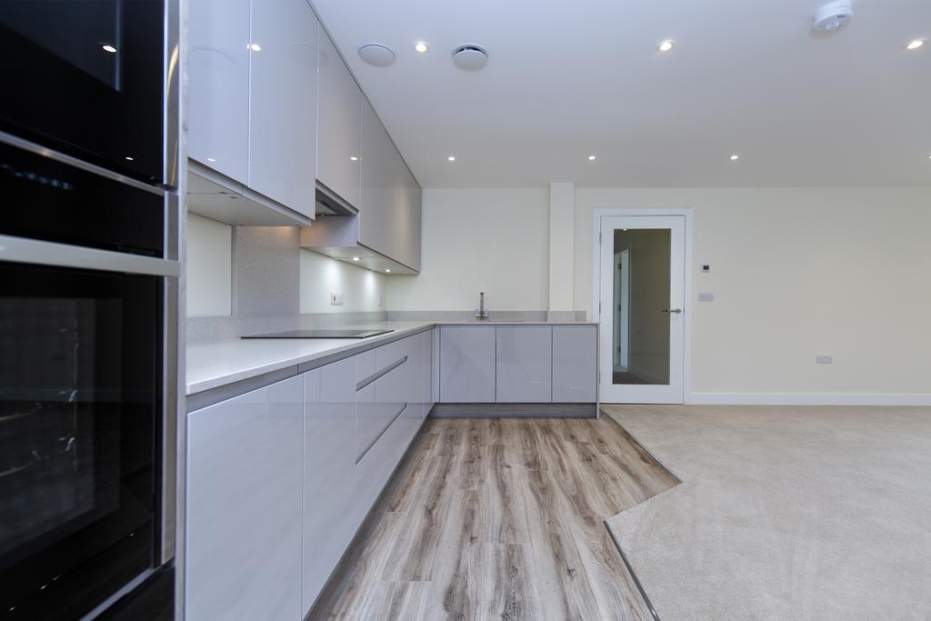 Spacious living kitchen with french doors to a balcony with glass balustrading