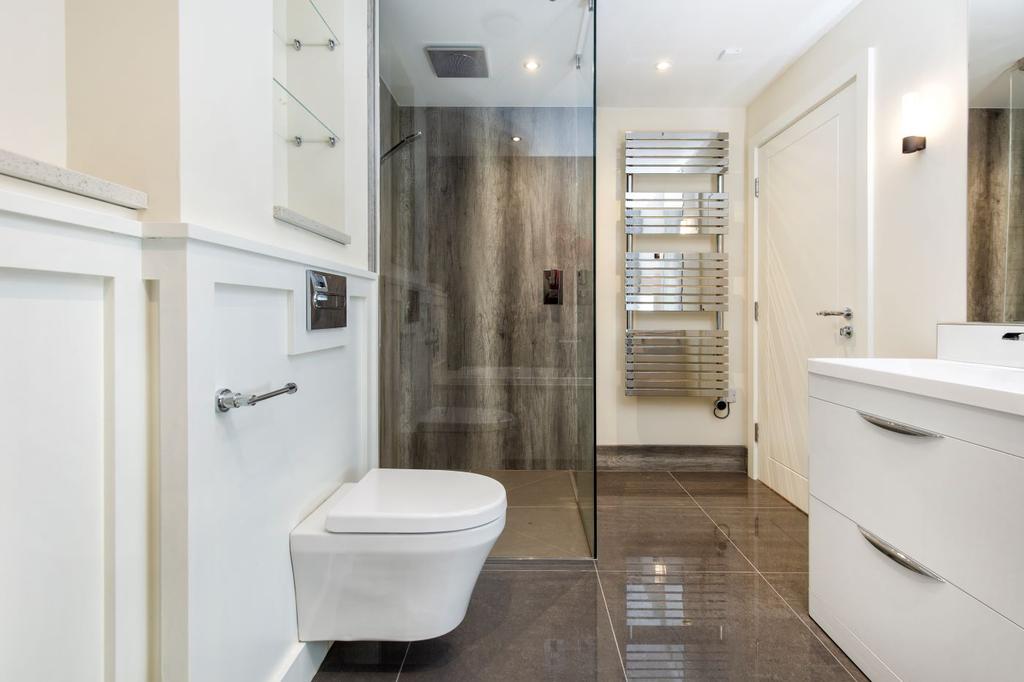 Large shower cubicle enclosed with a light marble effect waterproof panelling and floor to ceiling glass