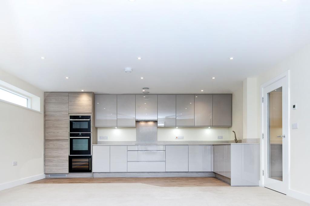 Open plan kitchen dining area with french doors to a balcony with glass balustrading displaying lots of light to the living spaces